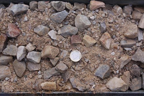 Un montón de rocas y tierra con una moneda en el medio.