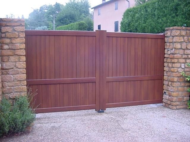 Portail en bois occultant composé de deux vantaux battants et de poteaux en pierre