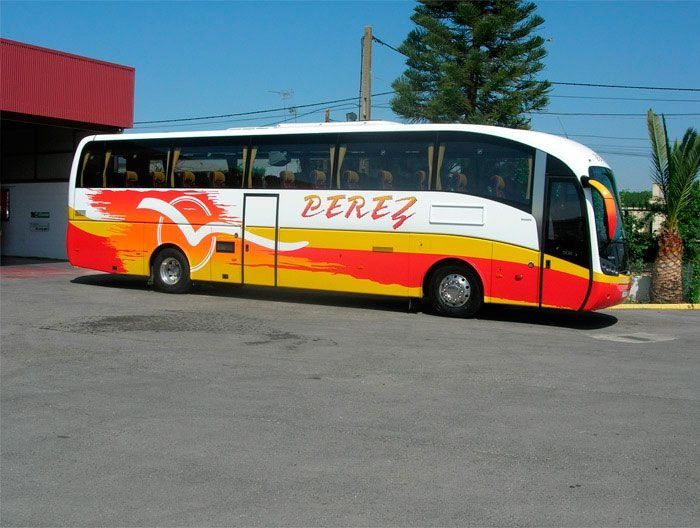Un autobús Pérez rojo y amarillo está estacionado en un estacionamiento.