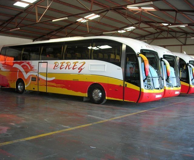 Una fila de autobuses Pérez están estacionados en un garaje.