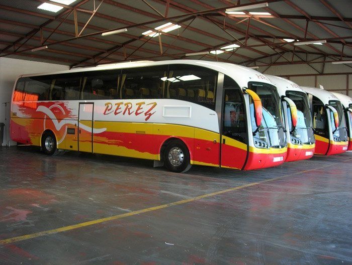 Varios autobuses Pérez están estacionados en un garaje.