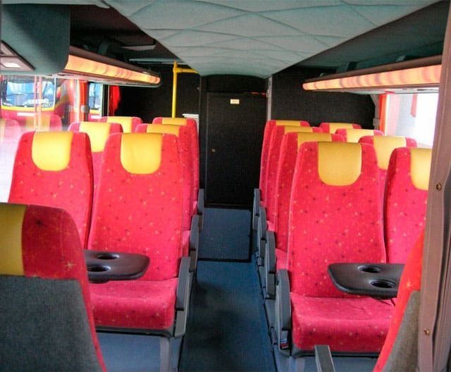 El interior de un autobús con asientos rojos y amarillos.