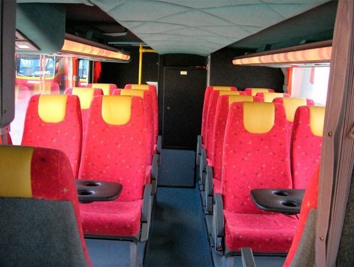 El interior de un autobús con asientos rojos y amarillos.