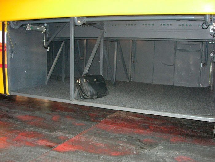 El maletero de un autobús amarillo tiene una maleta dentro