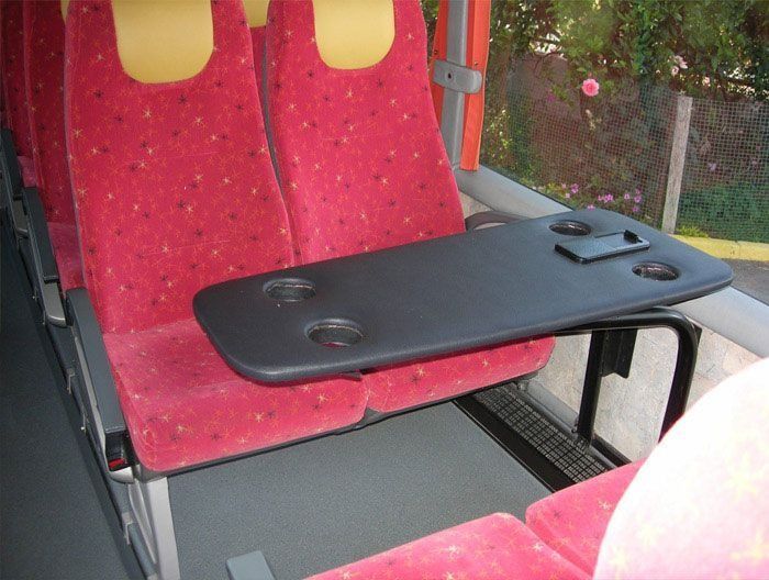 Un asiento rojo con una mesa negra adjunta.