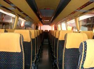 El interior de un autobús vacío con fundas de asientos amarillas.