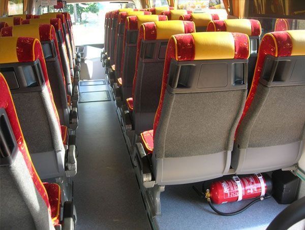 El interior de un autobús con asientos rojos y amarillos.