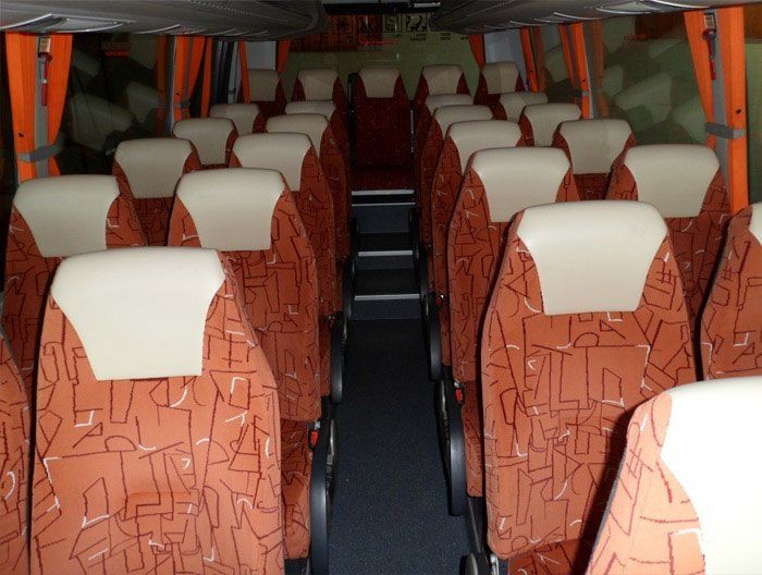 El interior de un autobús con muchos asientos y escaleras.