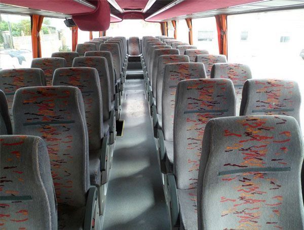 El interior de un autobús con asientos grises y rojos.