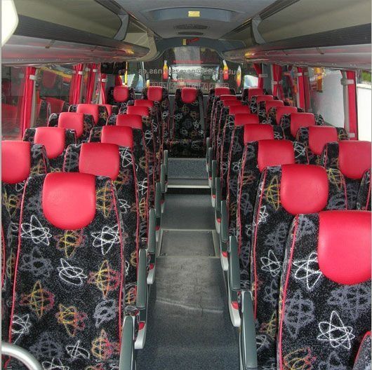 El interior de un autobús con asientos rojos y negros.