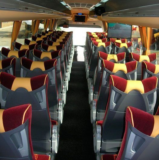 El interior de un autobús con asientos rojos y amarillos.