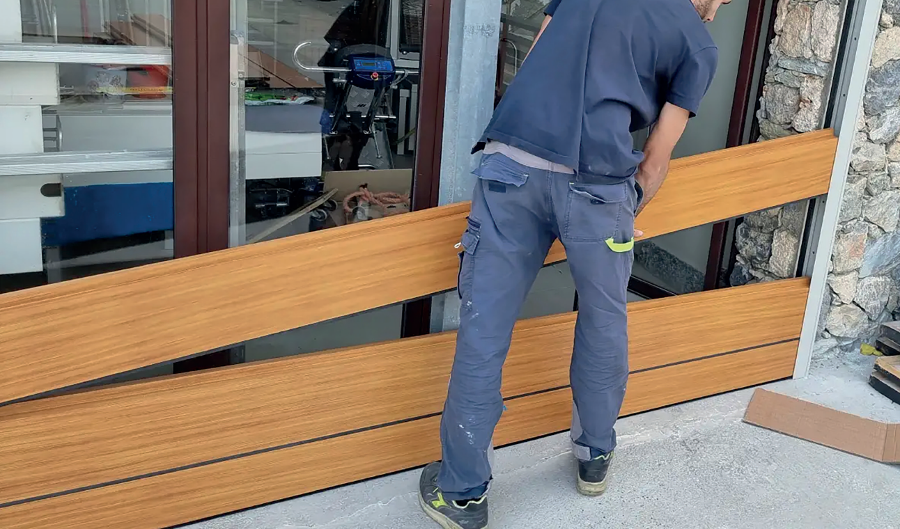 Ein Mann in blauen Hosen steht neben einem Holzgeländer.