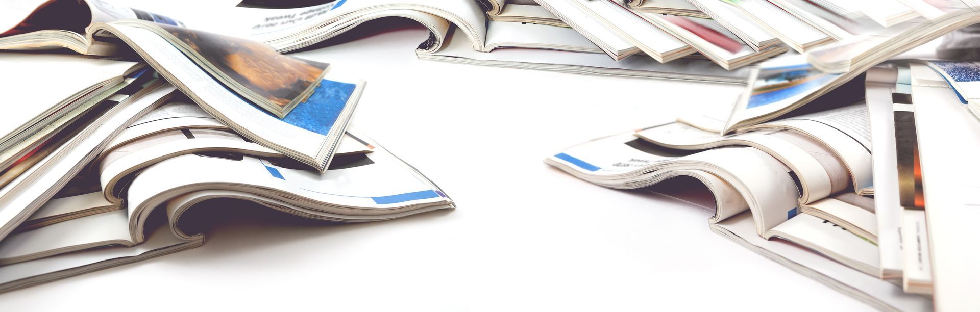 Journaux ou magazines éparpillés sur une surface blanche, avec des pages bleues et noires visibles