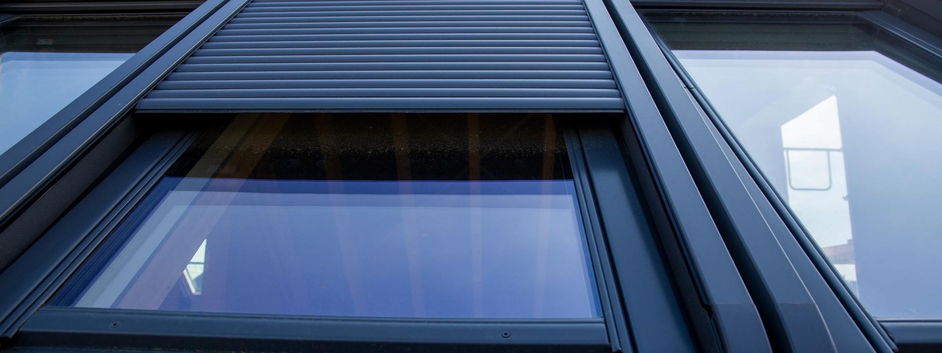 Façade d'un bâtiment moderne avec des panneaux sombres et une fenêtre réfléchissante vue d'en bas