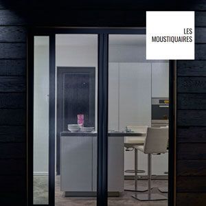 Intérieur de bureau vitré vu à travers des portes coulissantes, avec une chaise, un bureau et l'enseigne « Les Moustiquaires ».