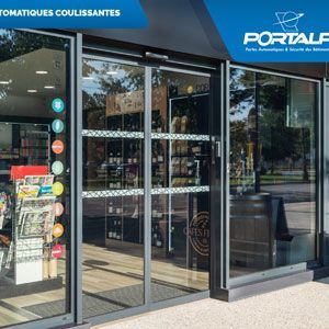 Façade avec portes coulissantes en verre et enseigne bleue, indiquant l'entrée d'un magasin moderne.