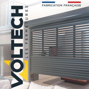 Portail roulant à lames gris-violet avec logo VOLTECH et inscription « Fabrication française » dans un showroom