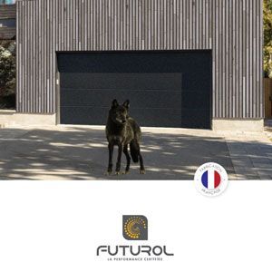 Chien noir debout devant un bâtiment gris moderne avec une grande porte de garage