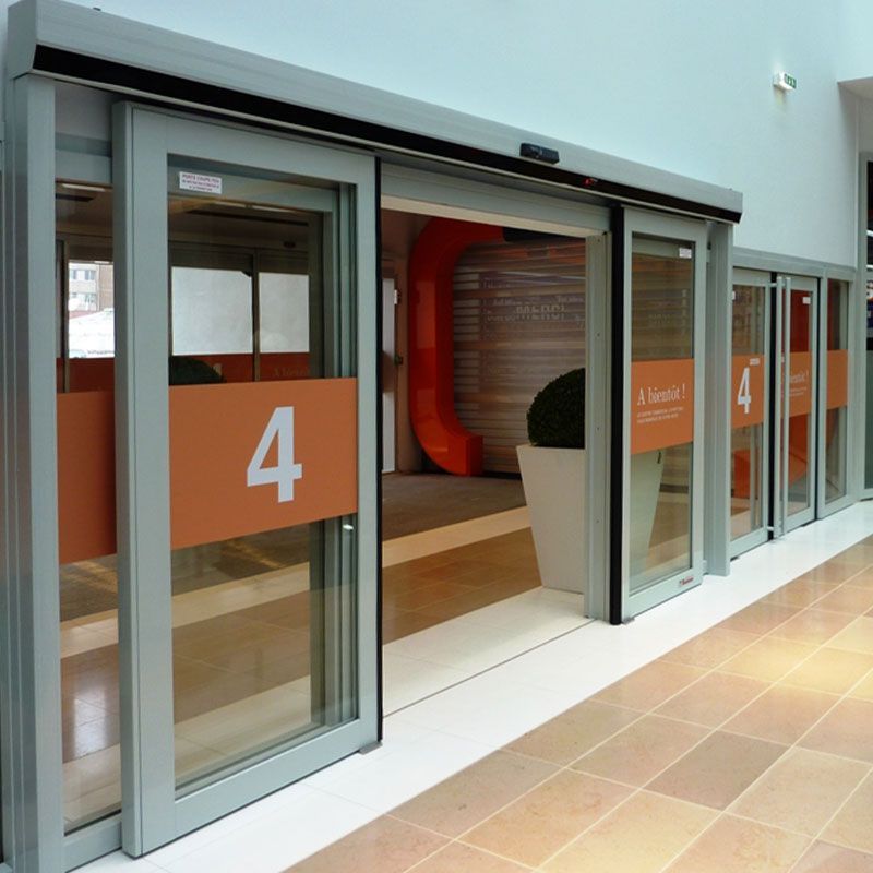 Portes coulissantes en verre numérotées 4 dans un couloir intérieur moderne avec des panneaux orange