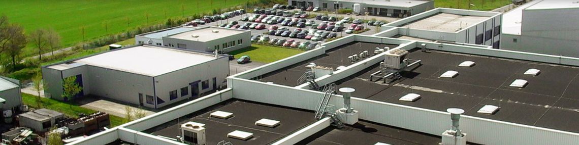 Firmengebäude aus der Vogelperspektive mit Parkplatz im Hintergrund