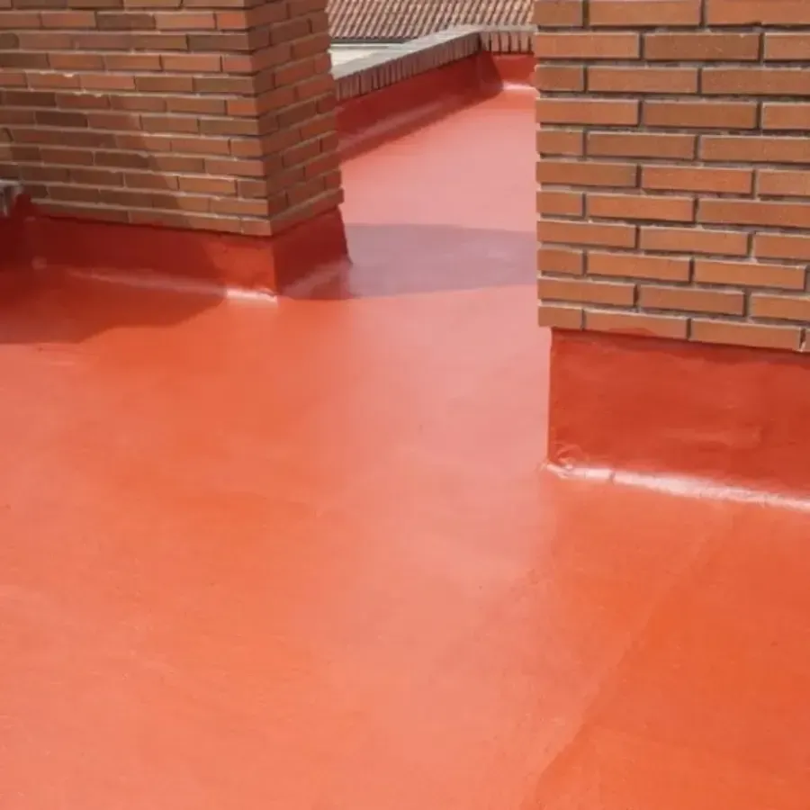 Techo revestido de rojo con columnas de chimenea de ladrillo, que muestra una superficie impermeable y exposición al sol.