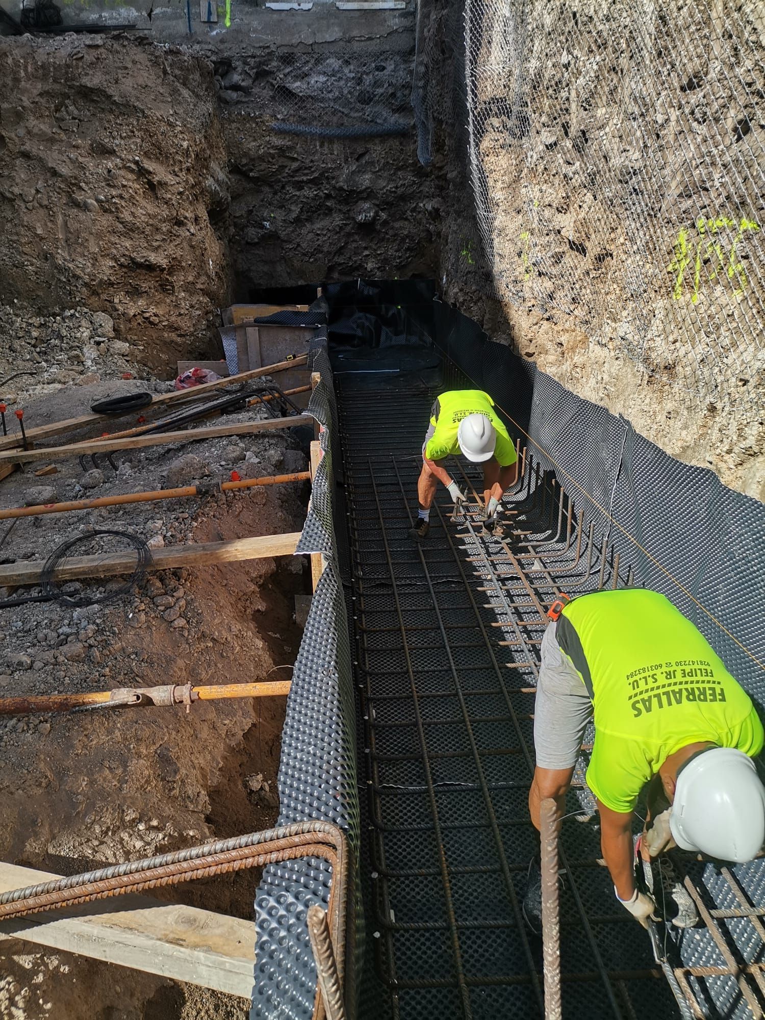 Dos obreros de la construcción están trabajando en un muro de hormigón.
