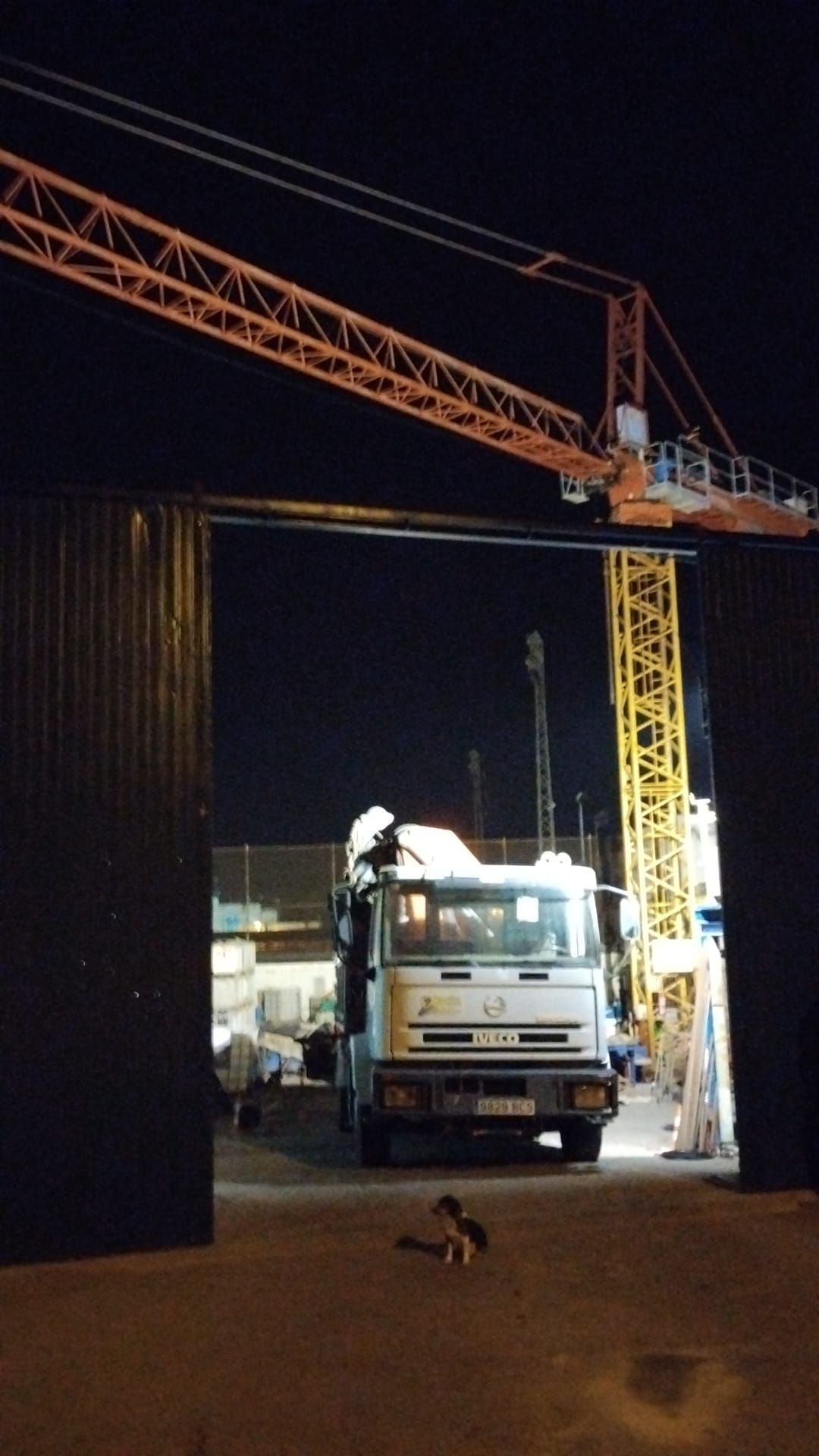 Un camión está estacionado debajo de una grúa por la noche.