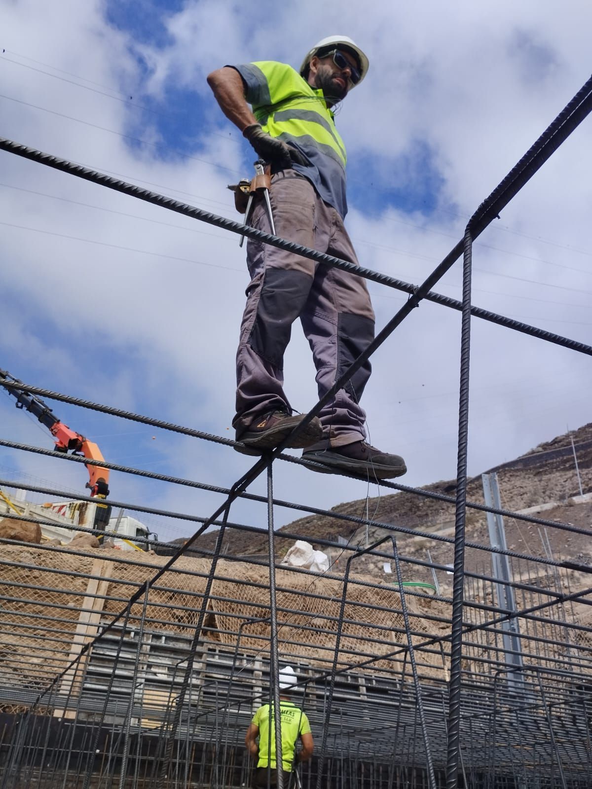 Un hombre con casco está parado sobre una cerca de alambre