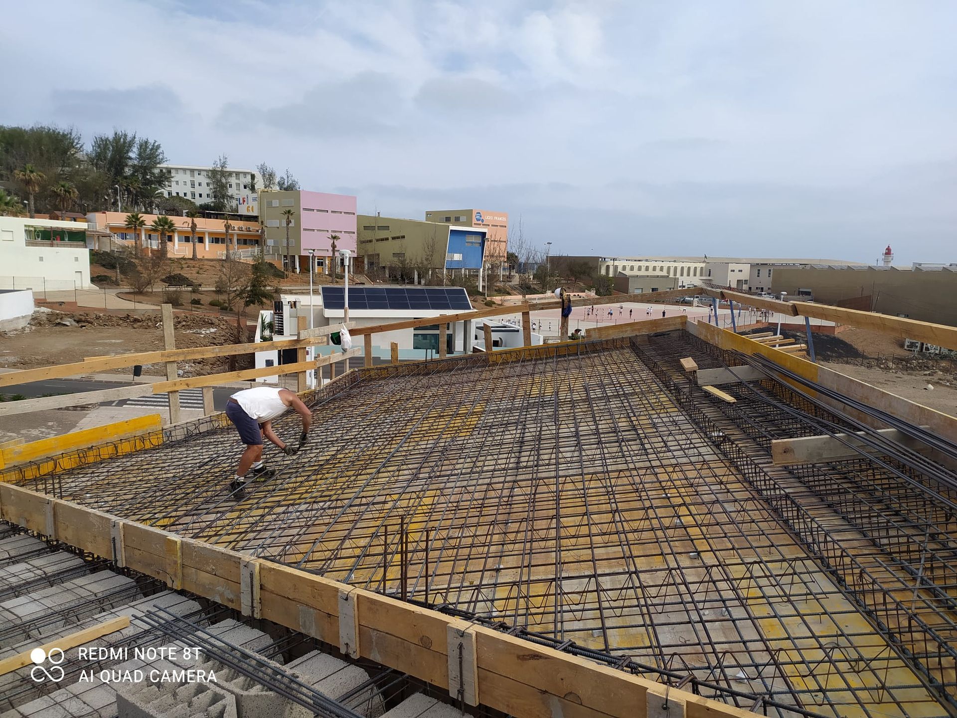 Un hombre está trabajando en un piso de concreto en un sitio de construcción.