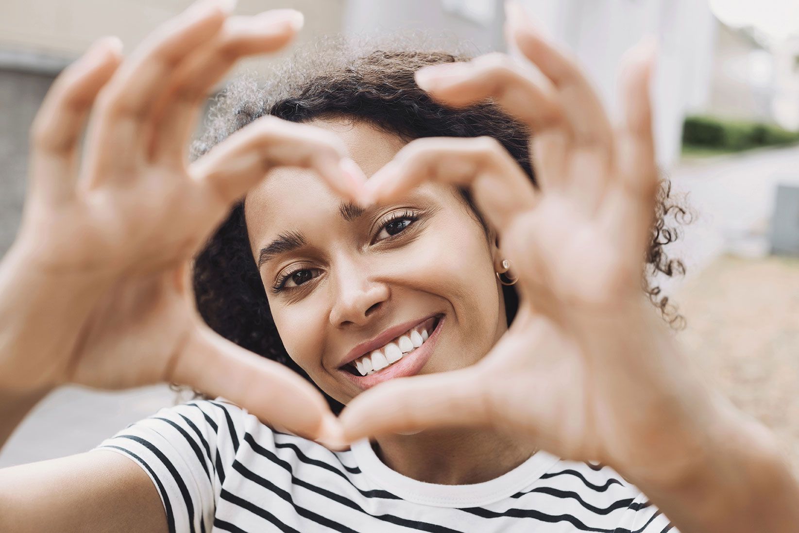 Belle femme souriante faisant une forme de cœur avec les mains en gros plan