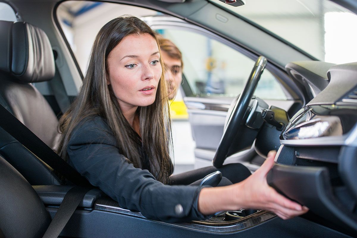 Femme qui inspecte une voiture d'occasion dans une concession