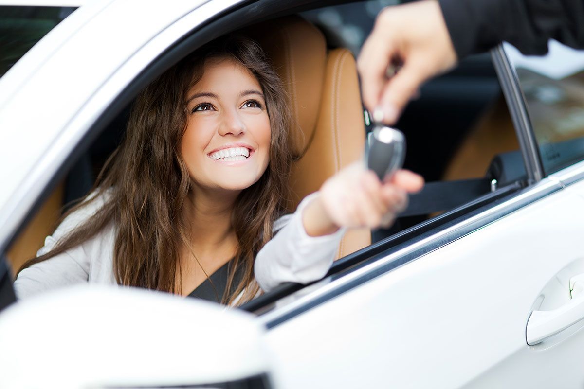 Homme qui donne les clefs à une femme dans une voiture blanche