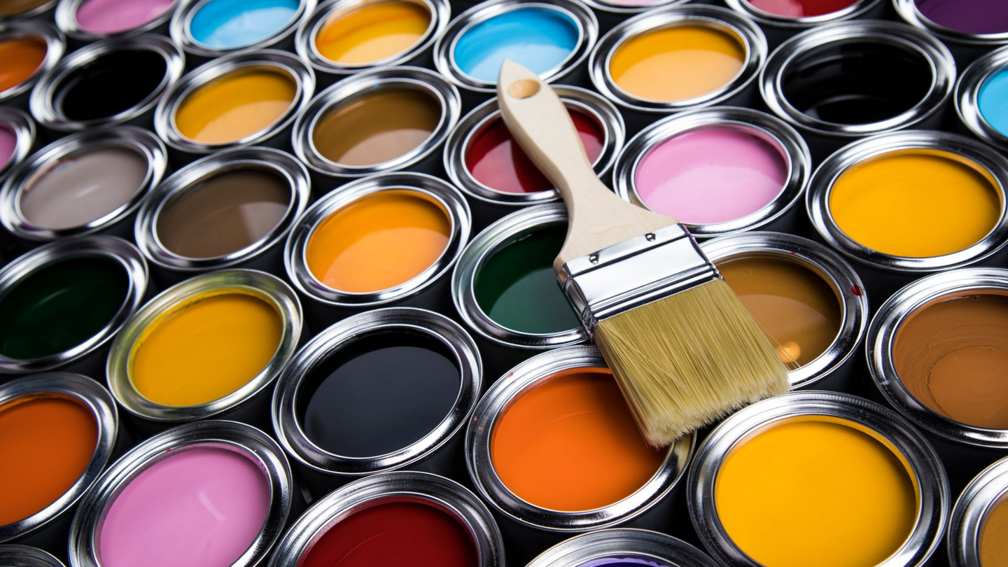 Un pinceau posé sur des pots de peintures multicolores