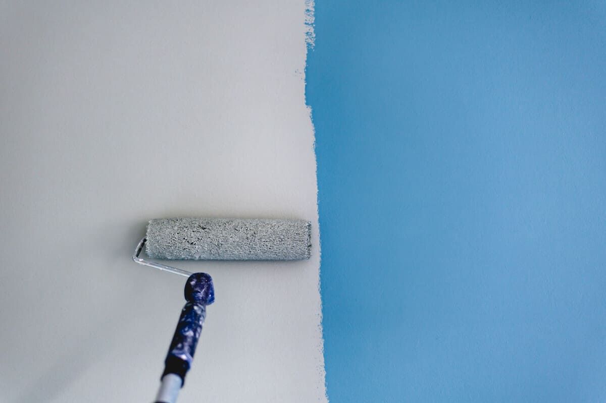 Una persona está pintando una pared azul con un rodillo de pintura.