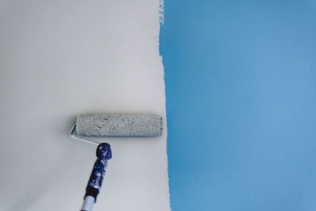 Una persona está pintando una pared azul con un rodillo de pintura.