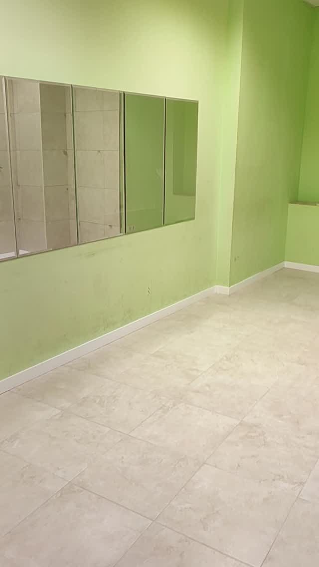 Una habitación vacía con paredes verdes y suelo de baldosas.