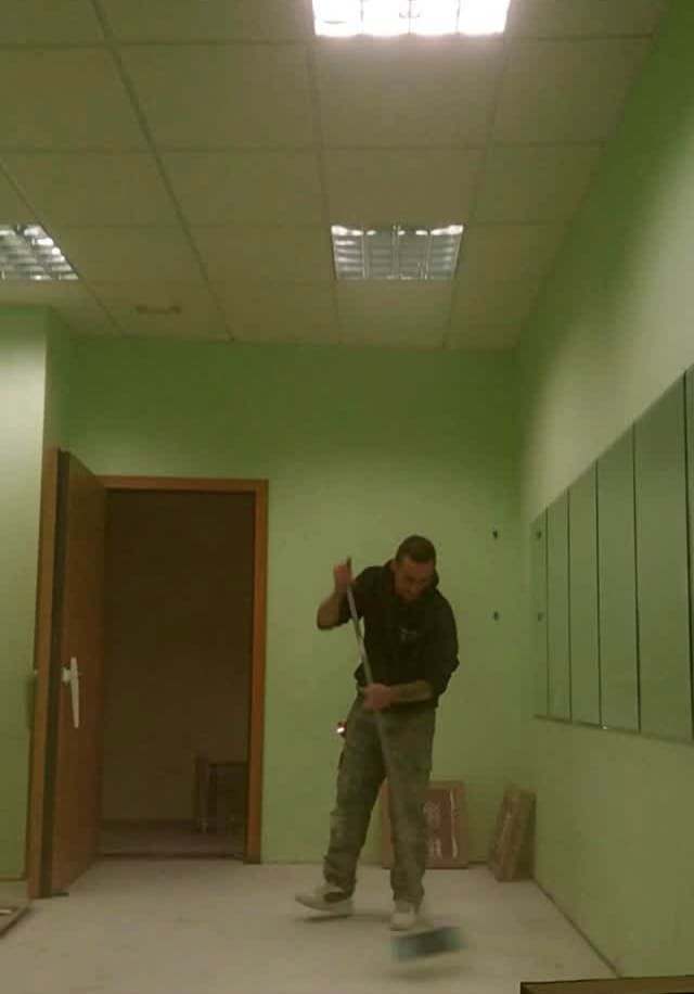 Un hombre está parado en una patineta en una habitación con paredes verdes.
