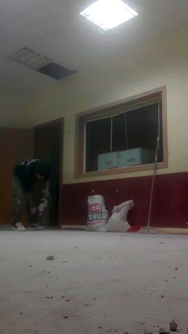 Un hombre está trabajando en el suelo de una habitación con ventana.