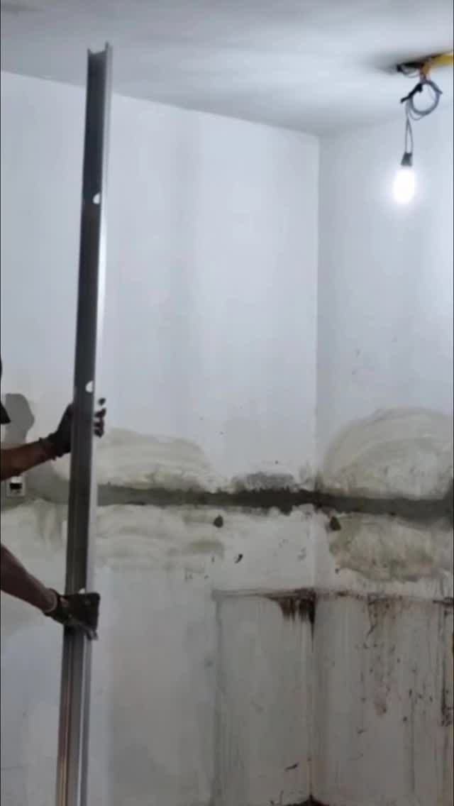 Un hombre sostiene un poste de metal en una habitación.