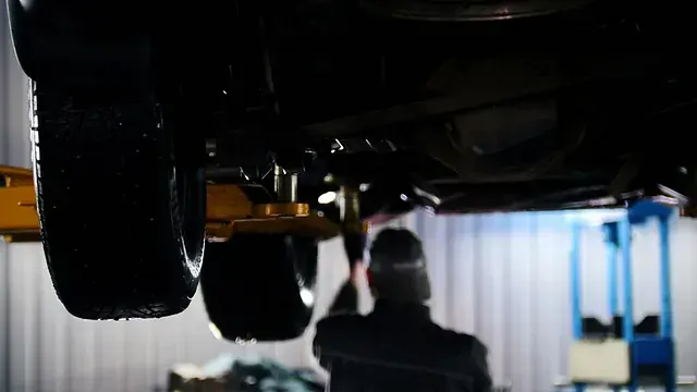 Un hombre está trabajando en la parte inferior de un coche en un garaje.