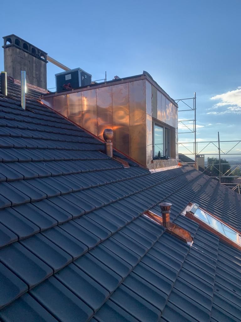 Gros plan sur un toit avec des éléments de ferblanterie et un Velux