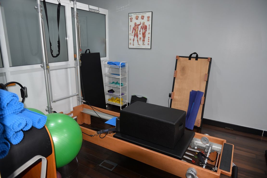 Una máquina de pilates está en una habitación al lado de una pelota verde.