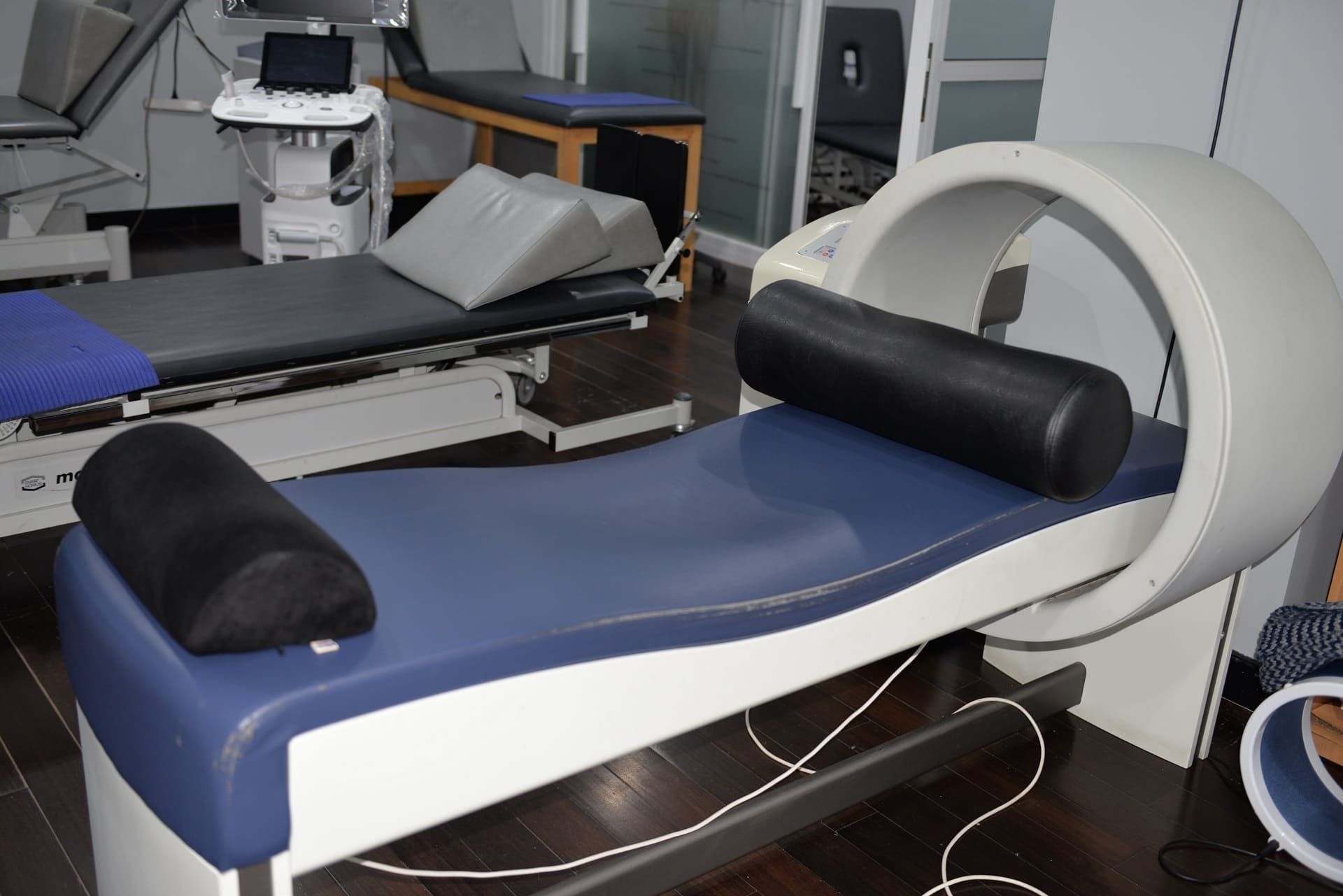 Una cama médica azul y blanca con una almohada negra encima.