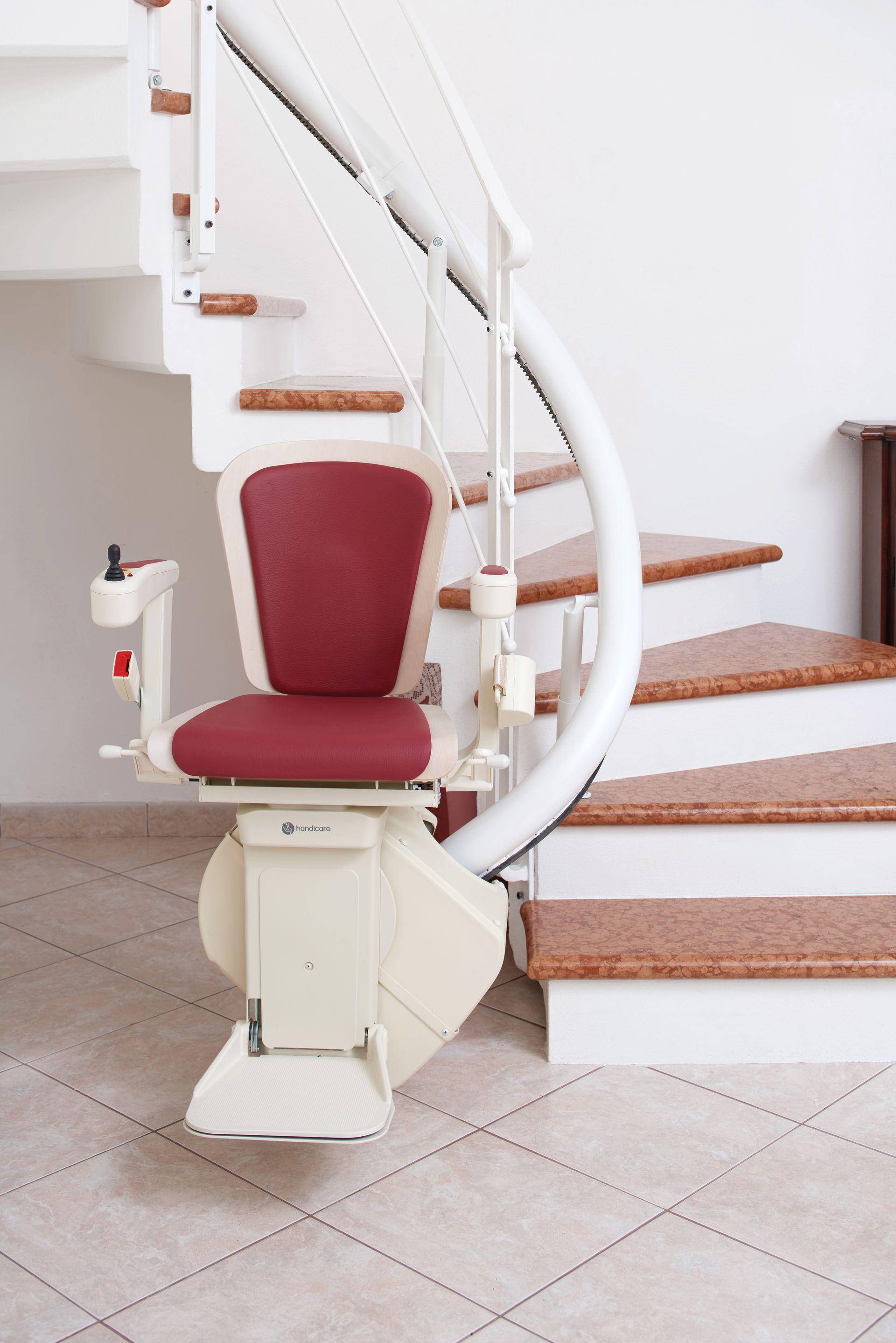 Monte-escalier incurvé avec siège rouge sur un escalier blanc et un sol carrelé