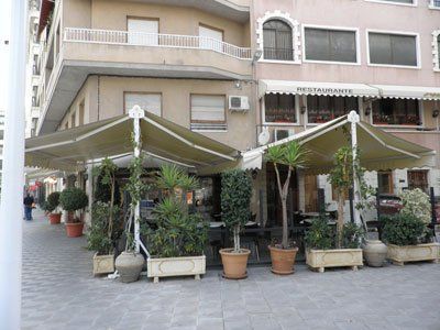 Un restaurante con sombrillas y plantas en macetas al aire libre.