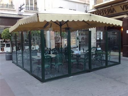 Una cafetería con mesas y sillas bajo una sombrilla.