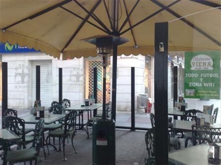 Un restaurante con mesas y sillas bajo una sombrilla y un cartel que dice viene todo futbol y zona wifi
