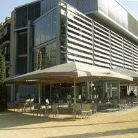 Un gran edificio con muchas ventanas y sombrillas en el frente.