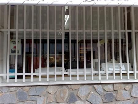 Una ventana con una valla metálica alrededor y un muro de piedra detrás.
