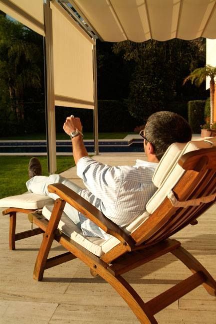 Un hombre está sentado en una silla de madera en un patio.